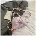 Detalle de bolso lavanda con lazo y colgante de corazón con correa ajustable en tela - Morado