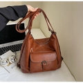 Detail of dark brown leather tote with metallic buckle in a minimalist urban office setting - Brown