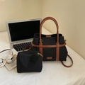 Dettaglio della borsa tote in tela nera con manici in pelle marrone vicino a un laptop - Nero