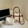 Dettaglio della borsa in tela con cinturini in ecopelle a contrasto e pochette interna su scrivania - Bianco Sporco