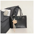 Close-up of black crocodile embossed tote bag with teddy bear charm and gold logo detail - Black