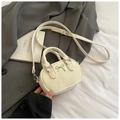 Detail view of mini cream bowling bag with silver bow on grey suit and white fabric - Off White