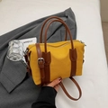 Detailed macro view of yellow canvas Boston bag with brown leather straps and hardware - Yellow