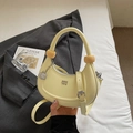 Detailed view of yellow crescent handbag with glossy finish and metal G-letter charm - Yellow