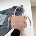 Elegant light pink square handbag with top handle and crossbody strap in professional setting - Pink