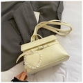 Detailaufnahme der beigen PU-Handtasche mit Spitzen-Herzanhänger und Schnallenriemen - Gelb