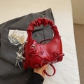 Close-up of bright red pleated handbag featuring a bow ornament and silver star charm - Burgundy