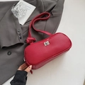 Minimalist red underarm bag with lychee texture and silver twist lock on a grey suit - Red