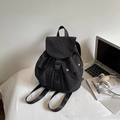 Close-up of black checkered backpack with buckle flap and drawstring next to laptop - Black