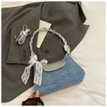 Detail of blue denim underarm bag featuring a silver flap and delicate white lace bow - Dark Blue