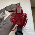Chic red patent leather bucket bag with dog charm and adjustable shoulder strap - Red
