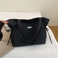 Detalle del bolso tote plisado negro con cordón lateral y etiqueta de marca en tela - Negro