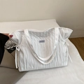 Detalle del bolso tote blanco a rayas con cordones laterales y textura de tela acolchada - Blanco