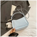 Close-up of light blue textured shoulder bag with silver chain and plush puppy charm - With Pendant / Blue
