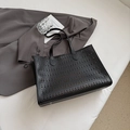 Black hollow-out tote bag with wide handles and metal studs on a minimalist background - Black