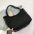 Large black canvas tote bag with white lettering and functional front pocket - Black