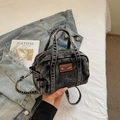 Close-up of black washed denim Boston bag featuring vintage texture and leather brand tag - Dark Brown