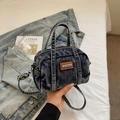 Detailed macro view showing the washed denim texture and leather logo on the handbag - Denim Blue