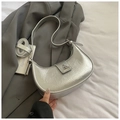 Macro detail of silver metallic crescent bag with pleated texture and geometric buckle - Silver
