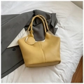 Detail of yellow lychee pattern leather tote bag with round charm on white fabric - Yellow