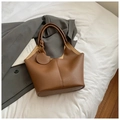 Close-up of brown litchi-grain tote bag with leather pendant and premium texture - Brown