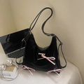 Schwarze Tragetasche mit rosa Seidenschleifen und Herznieten in lässiger Umgebung - Seidiges Schwarz