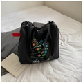 Close-up of black canvas tote bag featuring floral embroidery and tea me letter print - Black