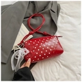 Close-up of red polka dot patent leather baguette bag with pearl mesh bow charm - Red with Pendant