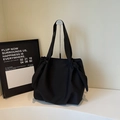 Detalle de un bolso tote de lona negro con elegantes nudos laterales y gran capacidad - Negro