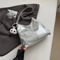 Macro view of silver metallic tote bag featuring pleated texture and a panda charm - Silver