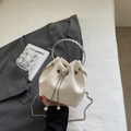 Detail der cremeweißen Satin-Beuteltasche mit silbernem Ringgriff und Schmetterlingsverschluss - Cremeweiß