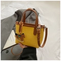 Detail of yellow woven tote bag featuring brown leather straps and wooden horse charm - Yellow