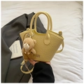 Details einer gelben Eimer-Tasche mit Krokoprägung, Logo und niedlichem Bären-Anhänger - Gelb mit Anhänger