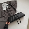 Detaillierte Nahaufnahme der schwarzen geflochtenen Ledertextur dieser modischen Baguette-Tasche - Schwarz