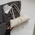 Detail einer cremefarbenen geflochtenen Tasche mit Fransen auf einem grauen Anzug - Weiß
