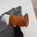 Detail der karamellfarbenen Baguette-Tasche mit Krokodilmuster und Silberkette - Braun