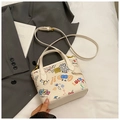 Detalle del bolso blanco con grafitis coloridos y correa ajustable sobre fondo suave - Estilo 1 Blanco