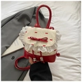 Detail van de rode strik en kant op een stijlvolle rugzak met een hartvormige hanger - Rood Wit Contrast Kant Stijl / Rood