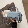 Detalle de bolso bandolera azul claro con textura tejida y hebilla metálica en la solapa - Azul
