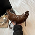 Dettaglio di una borsa a mezzaluna marrone scuro lucida con tracolla annodata e stile urbano - Marrone