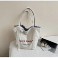 Dettaglio della borsa tote in tela bianca con fiocco in pizzo e fodera interna a righe blu - Blu