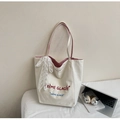 Dettaglio borsa tote in tela bianca con manici a righe rosse e fiocco di pizzo - Rosso