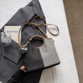 Detail van tweekleurige emmerzak met bruine leren handvatten en mini-hanger - Zwart