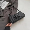 Detailansicht der schwarzen gewebten Baguette-Tasche mit Lederschleife auf Schreibtisch - Schwarz