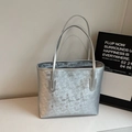 Detalle de un bolso tote plateado con un elegante estampado numérico y textura metálica - Plateado
