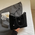 Bolso baguette negro moderno con detalle de lazo y acabado texturizado en escena elegante - Negro