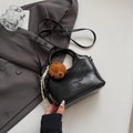 Detail der schwarzen Leder-Beuteltasche mit Teddy-Anhänger auf grauem Anzug-Hintergrund - Schwarz Mit Anhänger