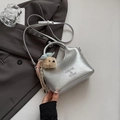 Détail du sac seau argenté en demi-lune avec bandoulière et breloque ours en peluche - Argent avec pendentif