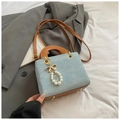 Detailed macro view of denim fabric texture, leather strap, and golden charm on the bag - Sky Blue With Pendant