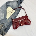 Detalle del bolso de hombro en charol burdeos con remaches plateados y hebillas metálicas - Rojo